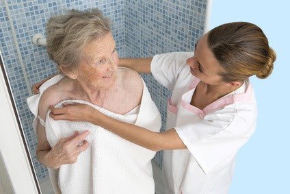 A nurse assisting an elderly woman in a shower, demonstrating compassionate care.