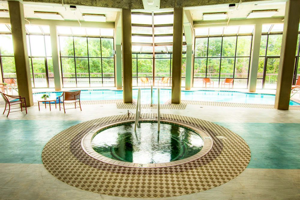 A serene indoor spa area featuring a hot tub and large windows providing a view of the outdoors.