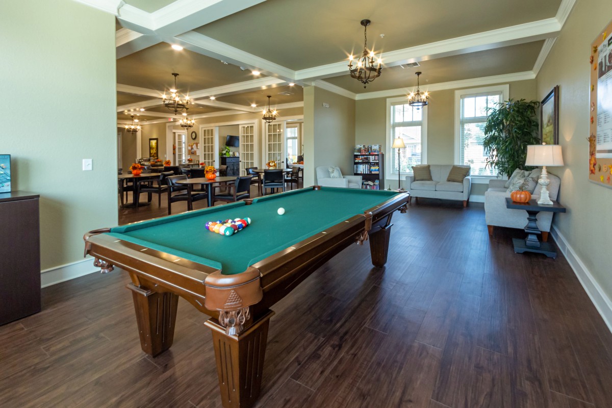 A spacious game room featuring a classic pool table and comfortable seating areas.