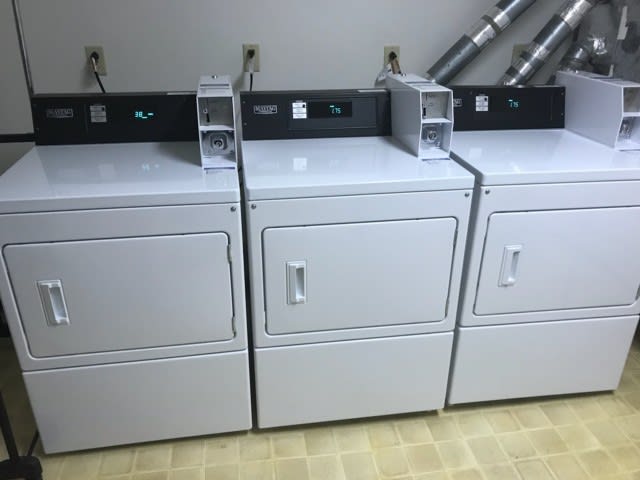 A row of three industrial dryers in a laundromat.