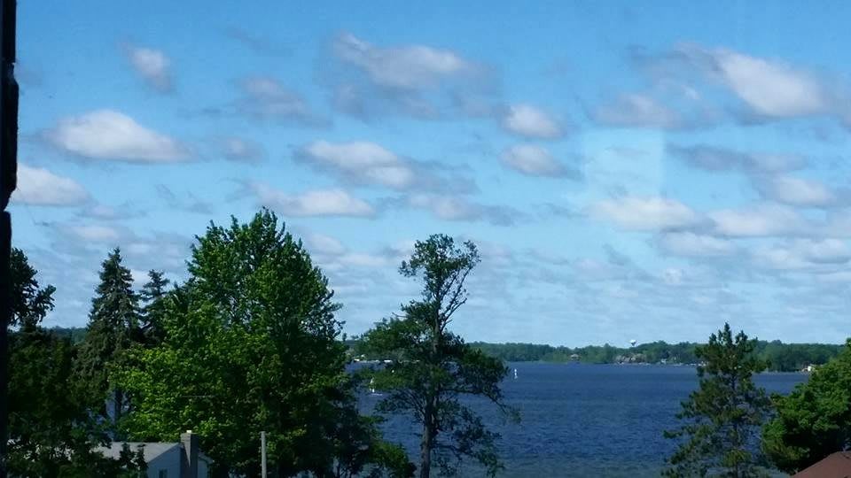 A peaceful lakeside view with trees and a partly cloudy sky.