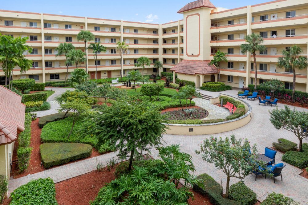 A well-maintained hotel courtyard surrounded by lush greenery and a multi-story building.