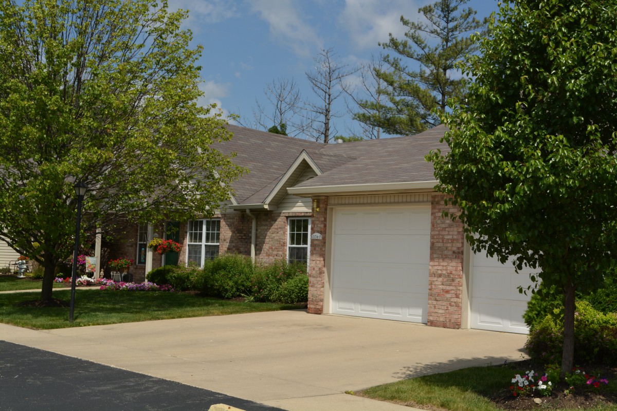 A suburban house with a driveway and garage surrounded by trees.