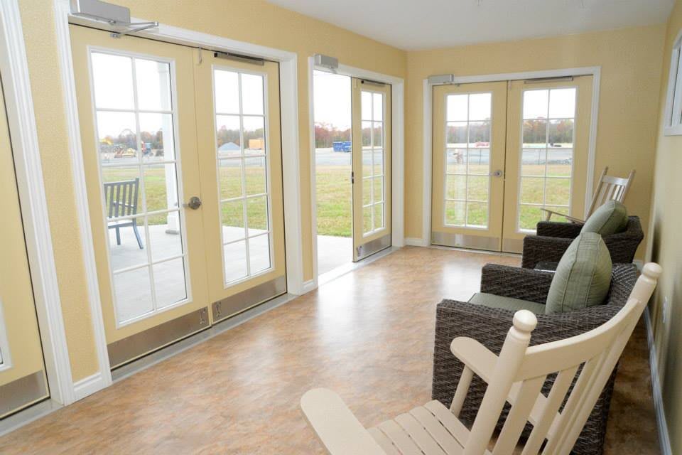 A bright sunroom featuring glass doors and comfortable furniture with a view of the patio.