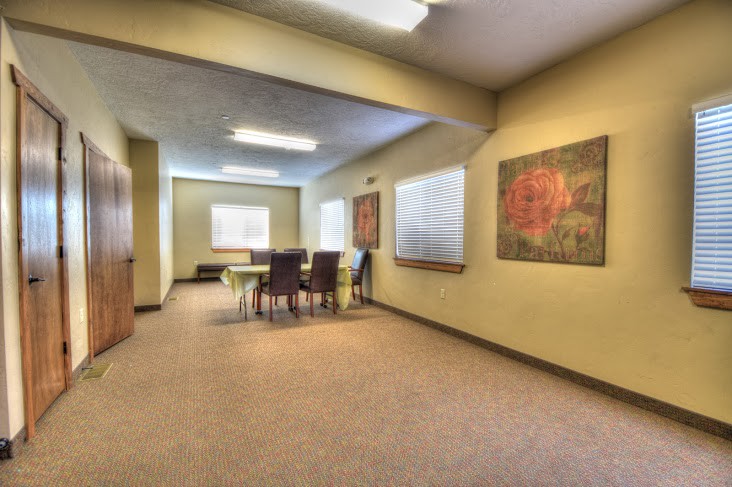 A spacious conference room with a large table and chairs, featuring artwork on the walls.