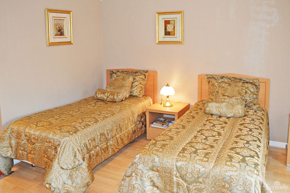 A cozy bedroom featuring twin beds with matching golden bedding and decorative wall art.