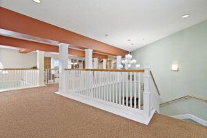 A modern interior hallway featuring a staircase with white railings and contemporary lighting.