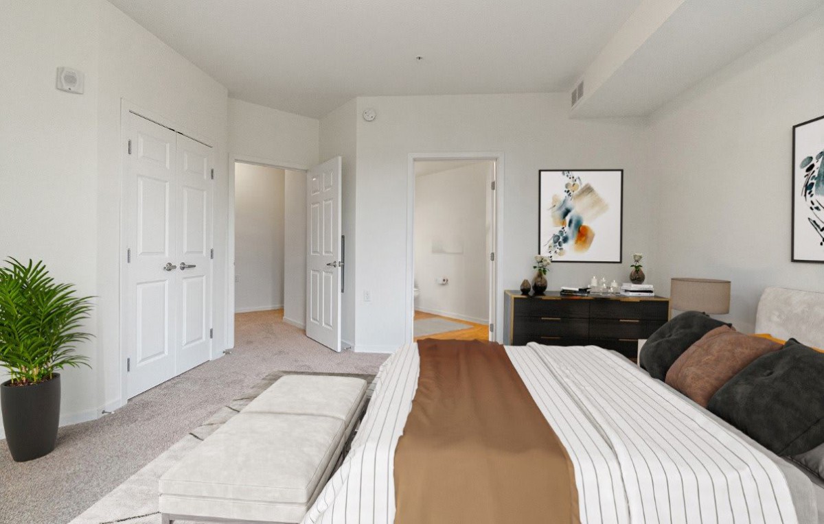 A modern bedroom with a neatly made bed, artwork on the wall, and a dresser.
