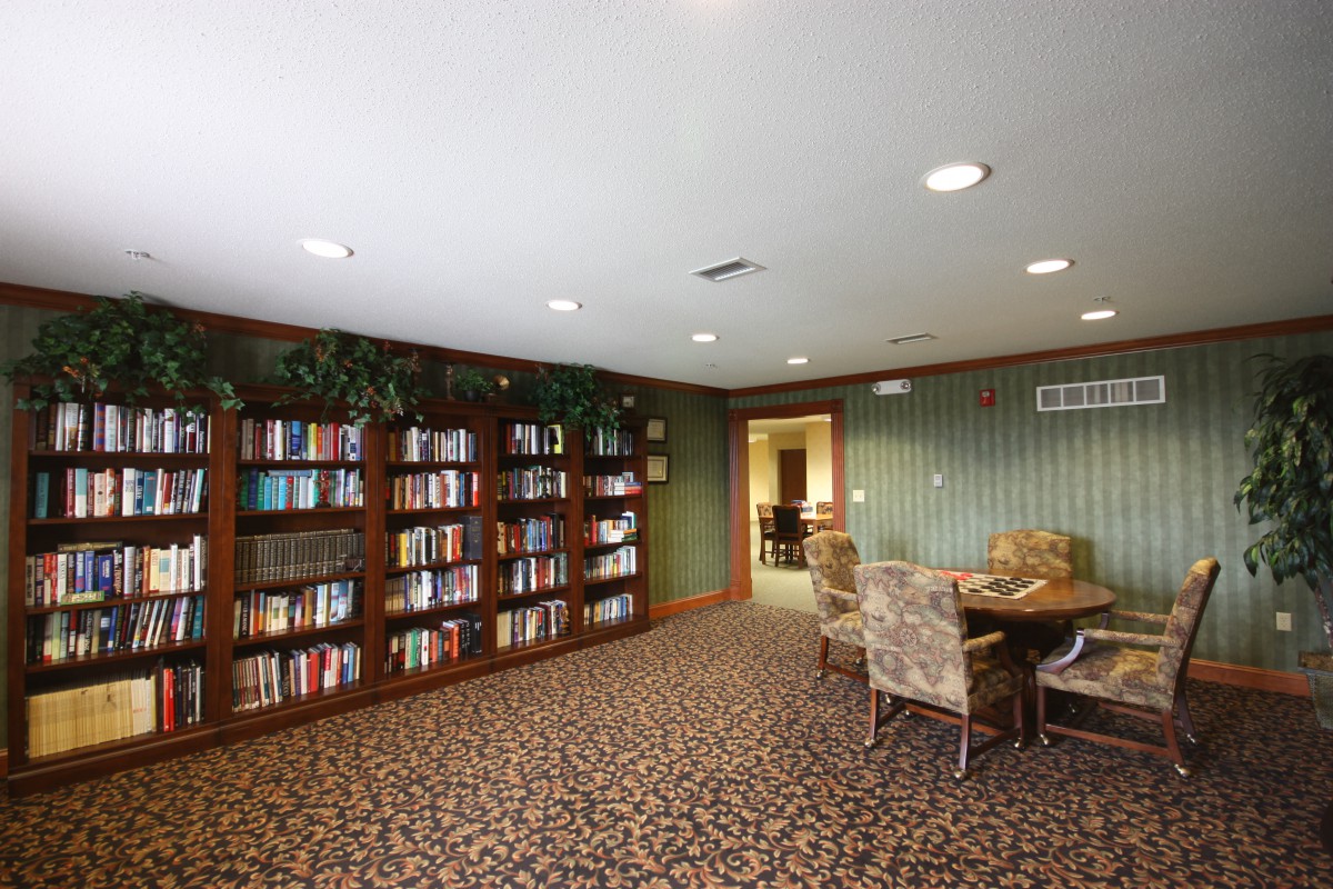 A cozy library room with bookshelves, a table, and chairs.