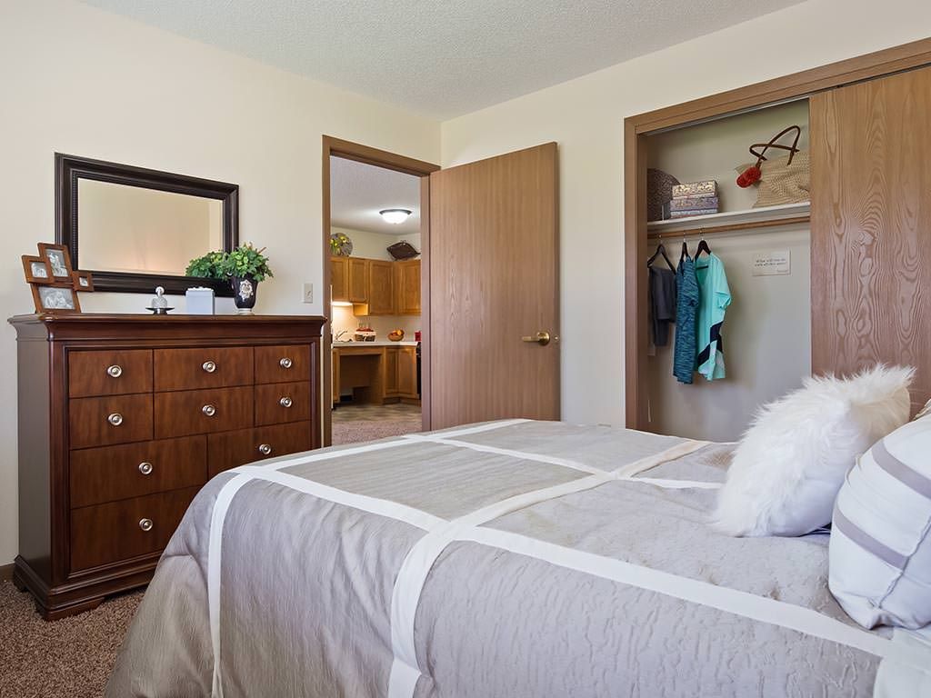 A cozy bedroom with a bed, dresser, and open closet.
