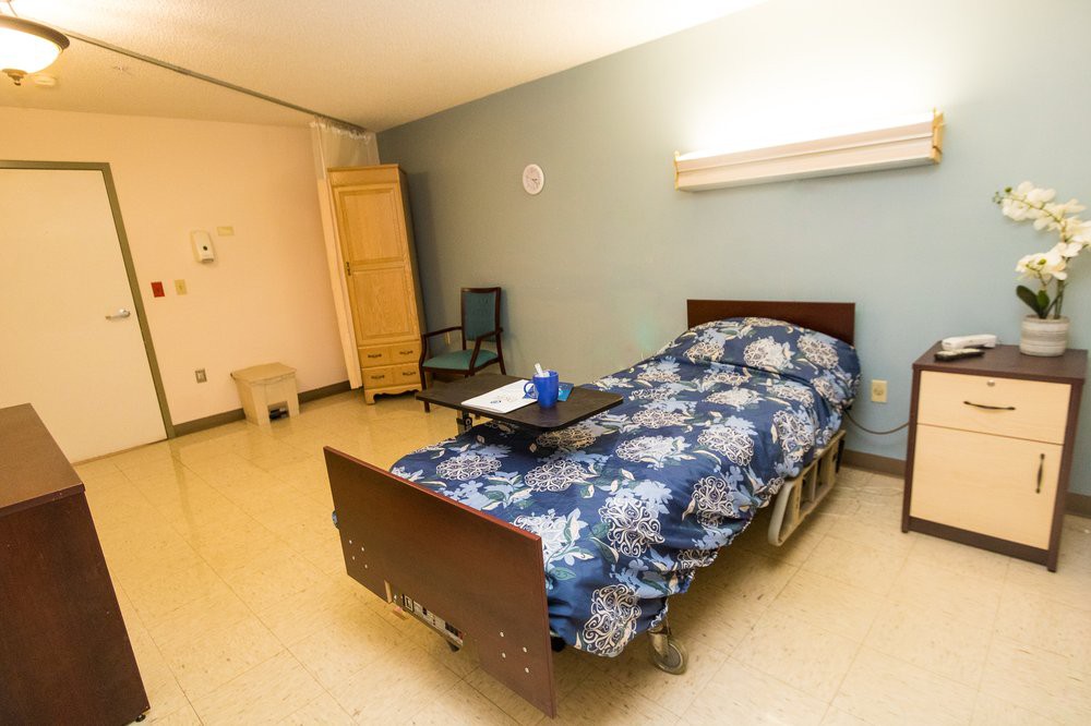 A simple hospital room with a single bed and basic furnishings.