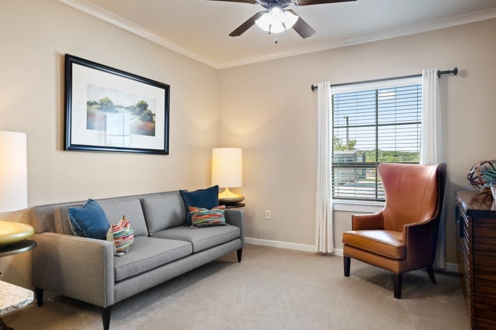 A cozy living room with a sofa, armchair, and a lamp near the window.