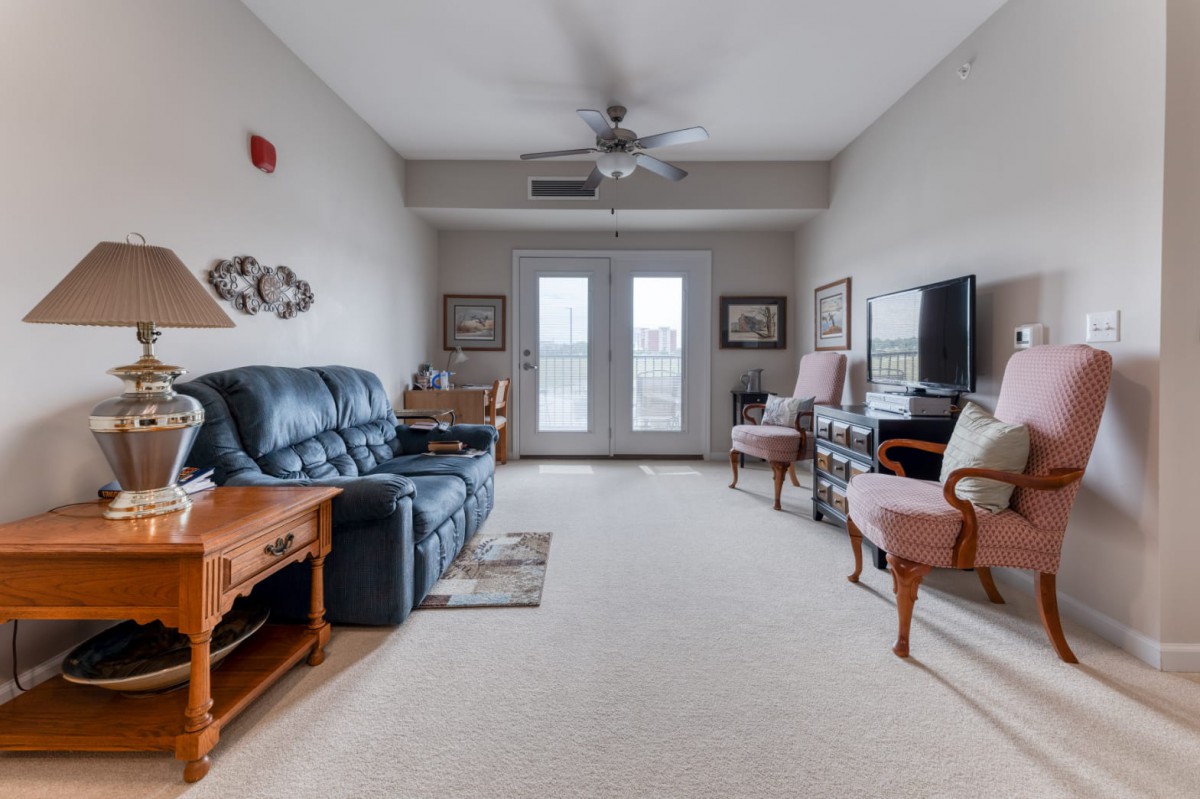 A cozy living room with a leather sofa, television, and large windows.