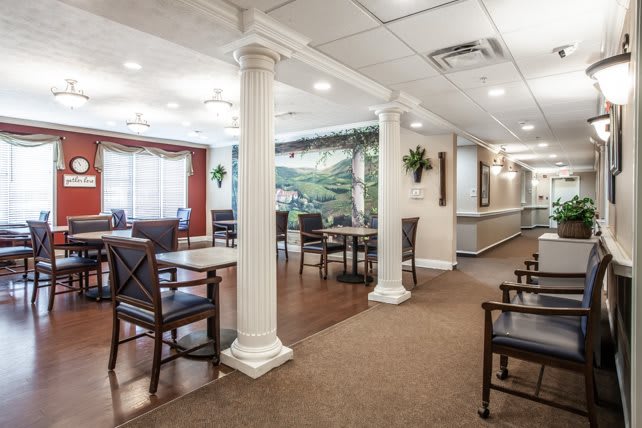 A well-lit dining area with tables, chairs, and decorative columns.