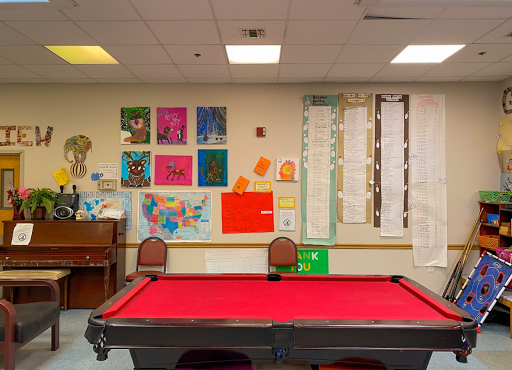 A vibrant game room featuring a red pool table and colorful art on the walls.
