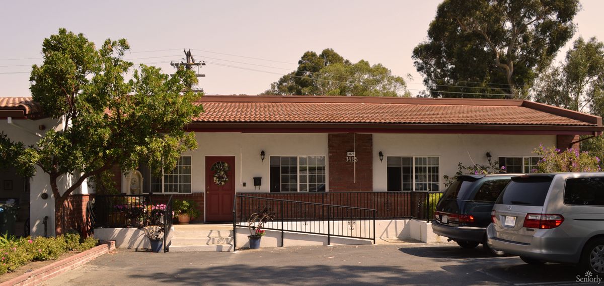 A quaint single-story building with a red door and surrounded by trees.