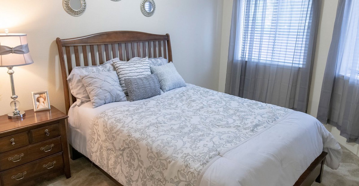 A cozy bedroom with a neatly made bed and decorative pillows.