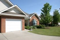 A suburban brick house with a garage and landscaped front yard.