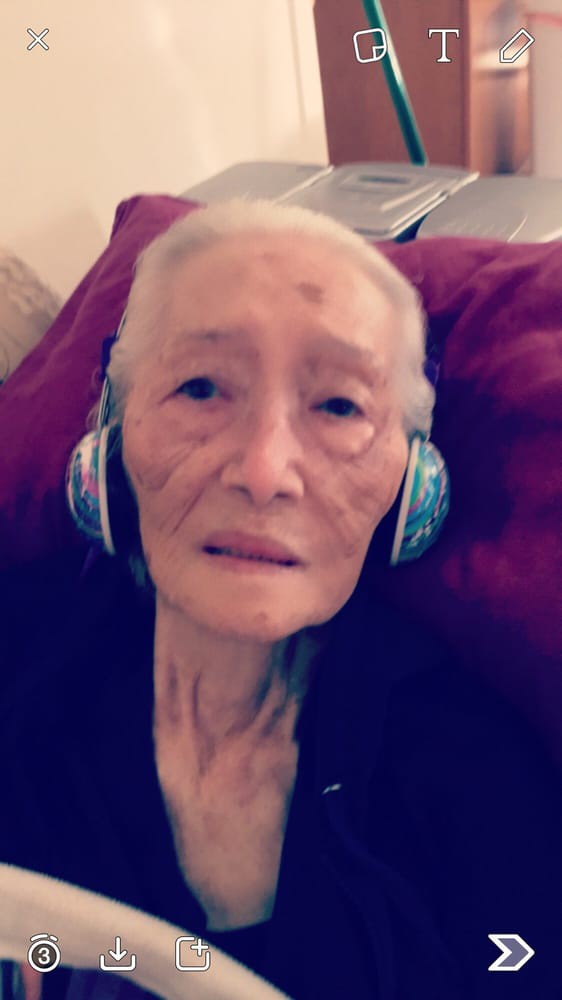An elderly person relaxing with headphones on.