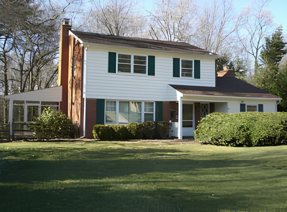 A suburban two-story house with a well-maintained lawn and surrounding trees.
