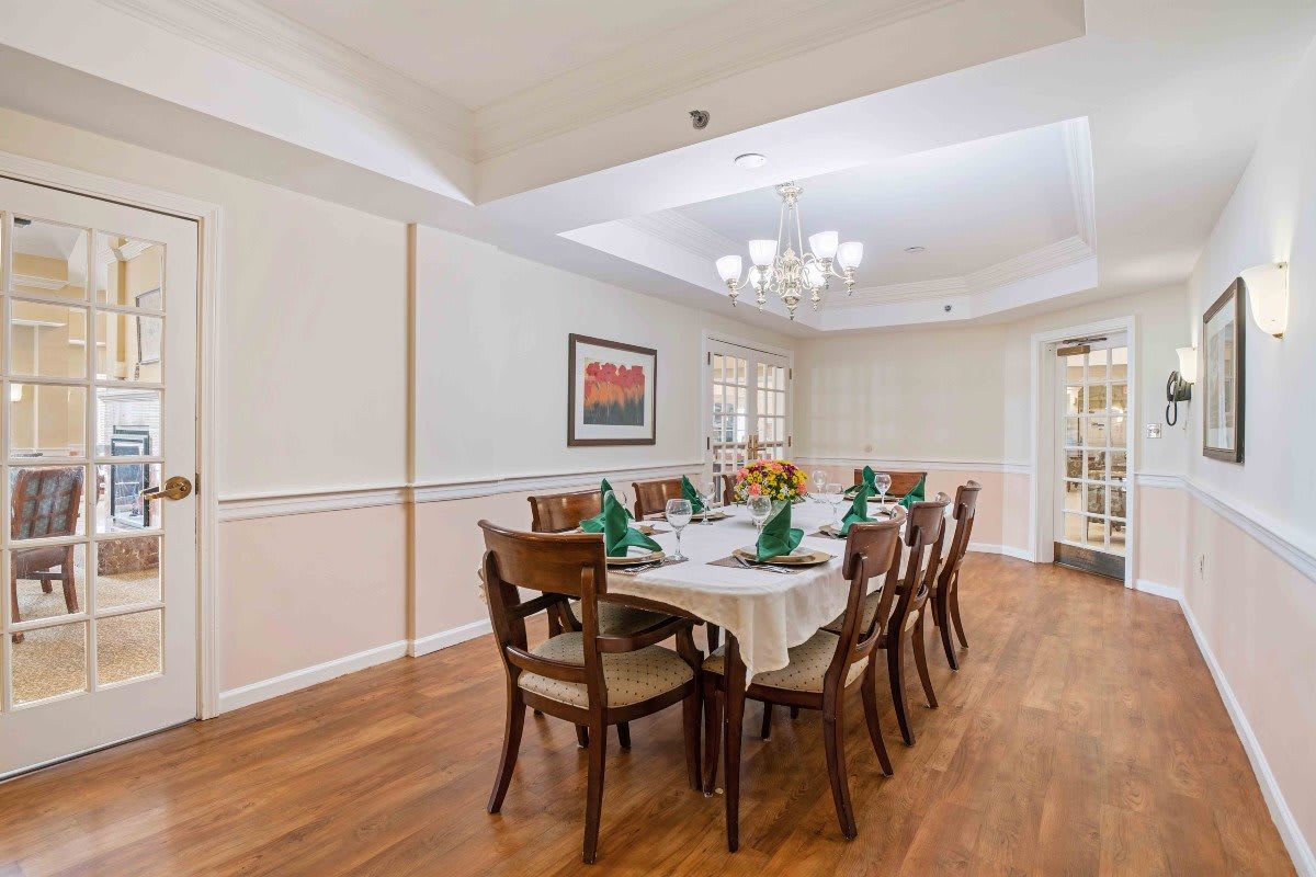 A well-appointed dining room with a long table, multiple chairs, and a chandelier hanging above.