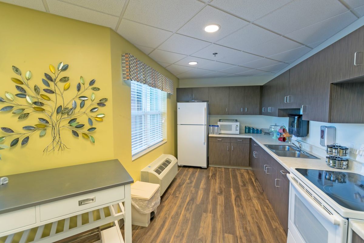 A modern kitchen with yellow walls, wood flooring, and white appliances.