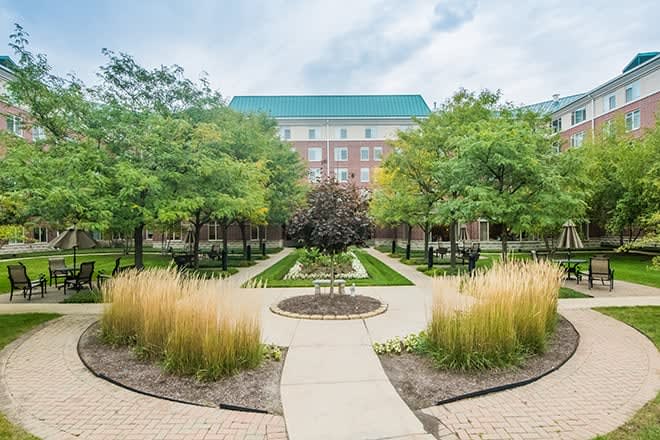 A beautifully landscaped garden with a pathway leading to a building surrounded by lush greenery.