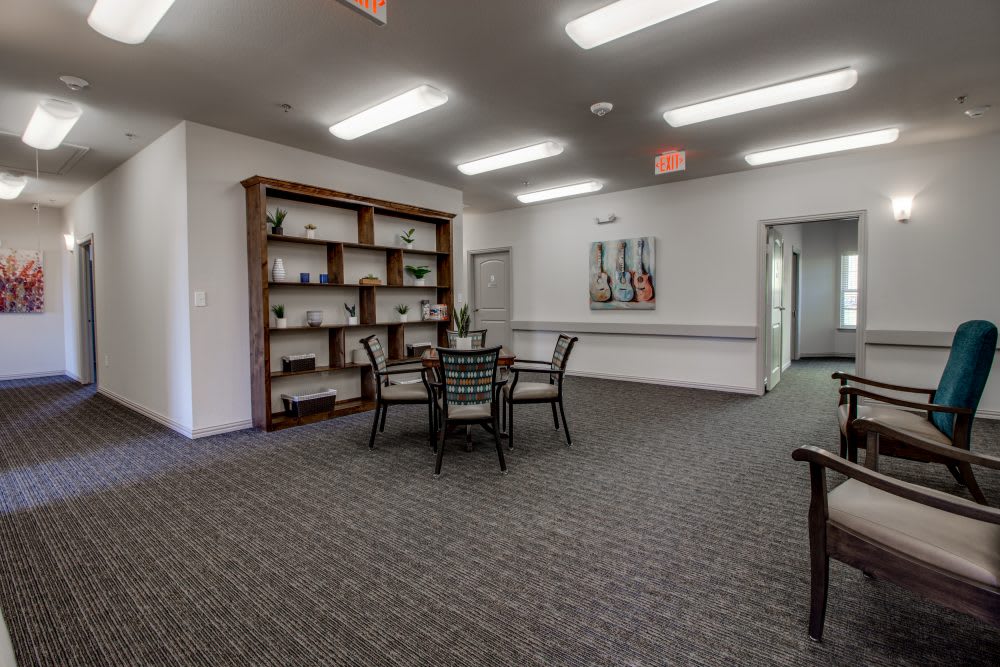 A quiet indoor room with a table, chairs, and a bookshelf.