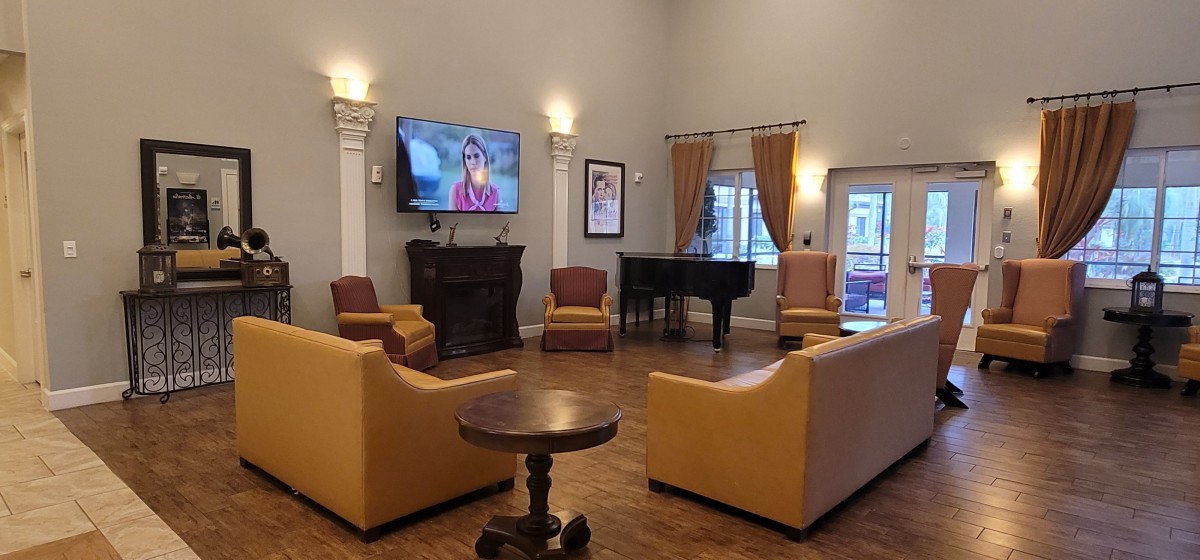 A cozy living room with a TV, seating area, and piano.
