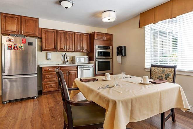 A cozy kitchen and dining area with wooden cabinets, featuring a dining table set for two.