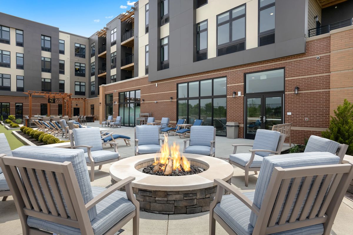 A modern apartment complex featuring an outdoor seating area around a fire pit.
