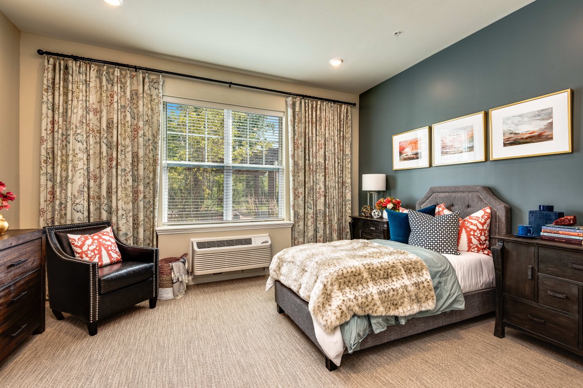 A cozy, well-decorated bedroom with a large window, bed, and various decorative elements.