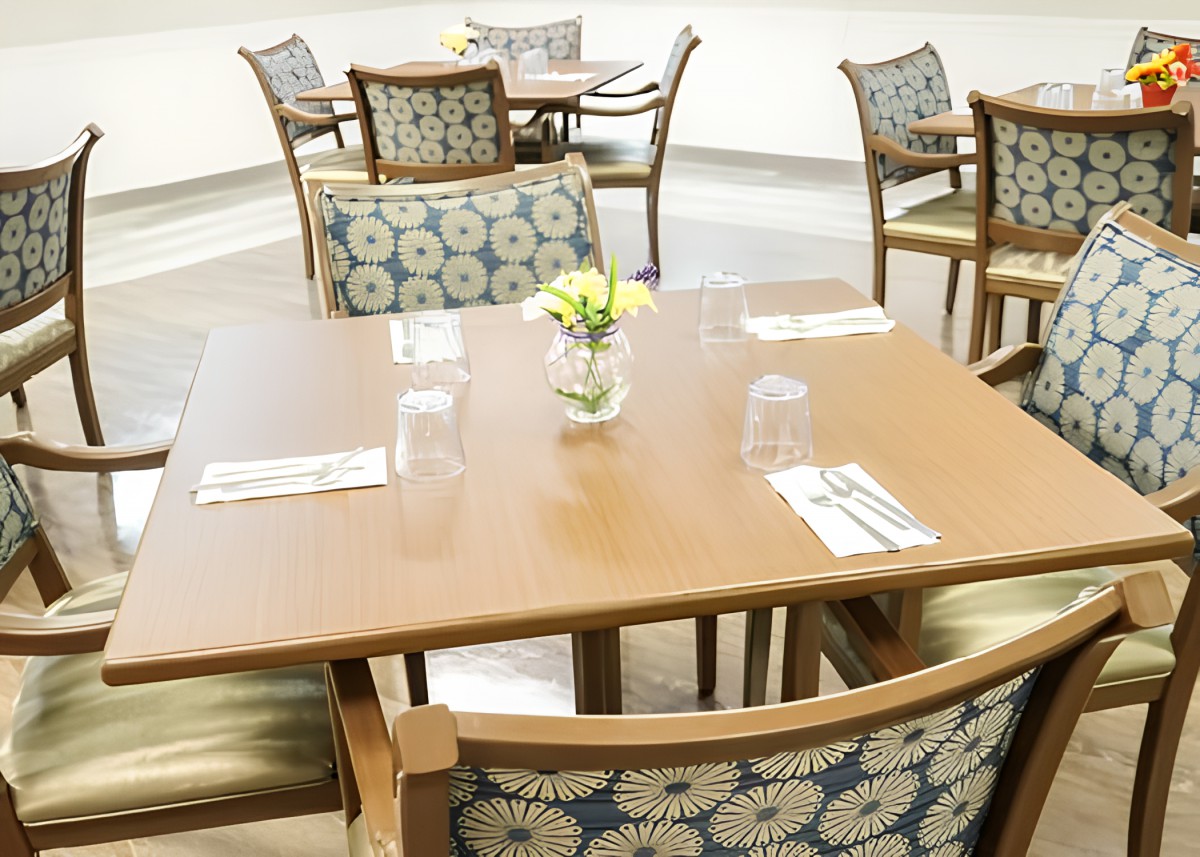 A cozy dining area with neatly arranged tables and chairs, featuring floral centerpieces.