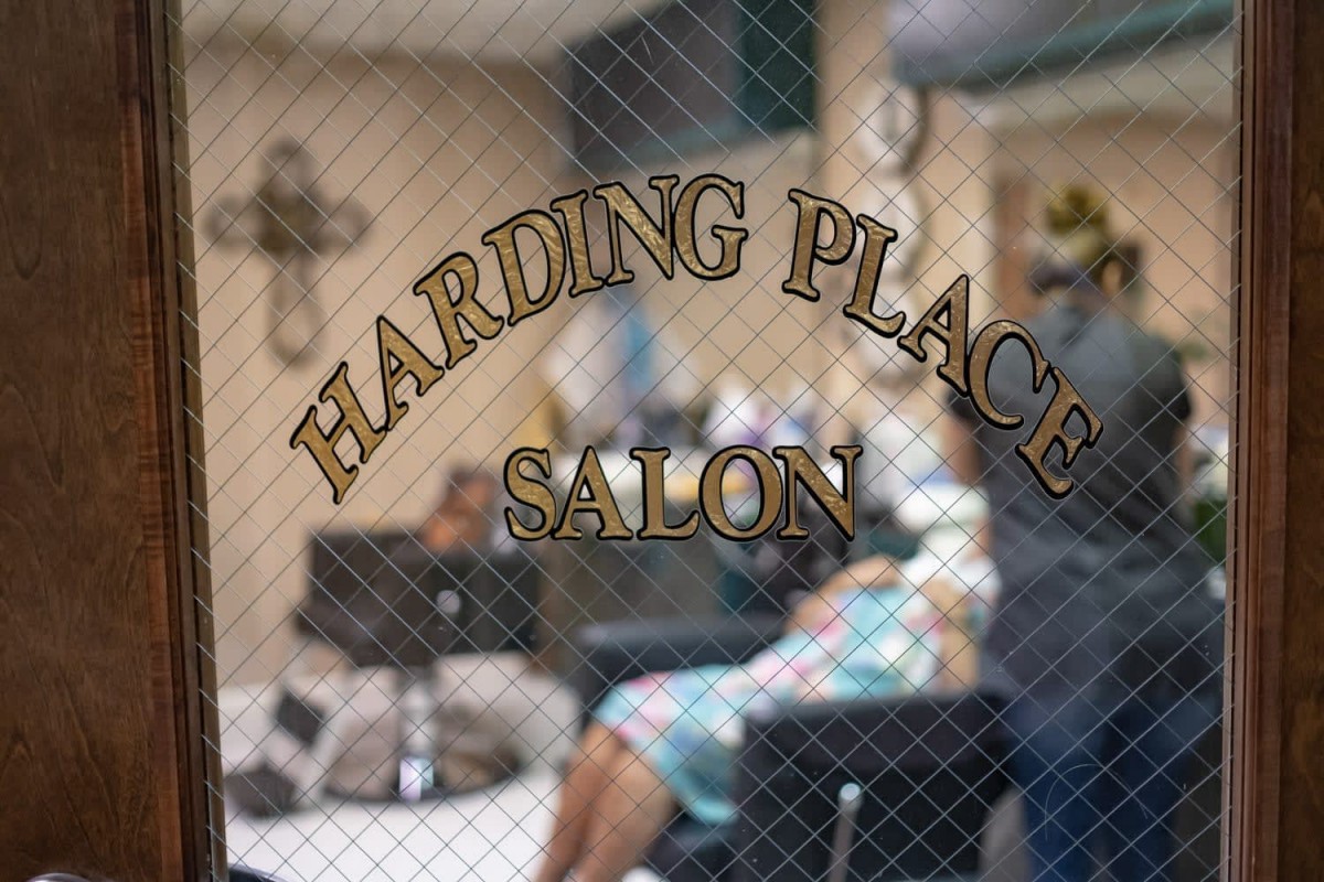 The view through the window shows a cozy salon interior with chairs and hairdressing equipment.