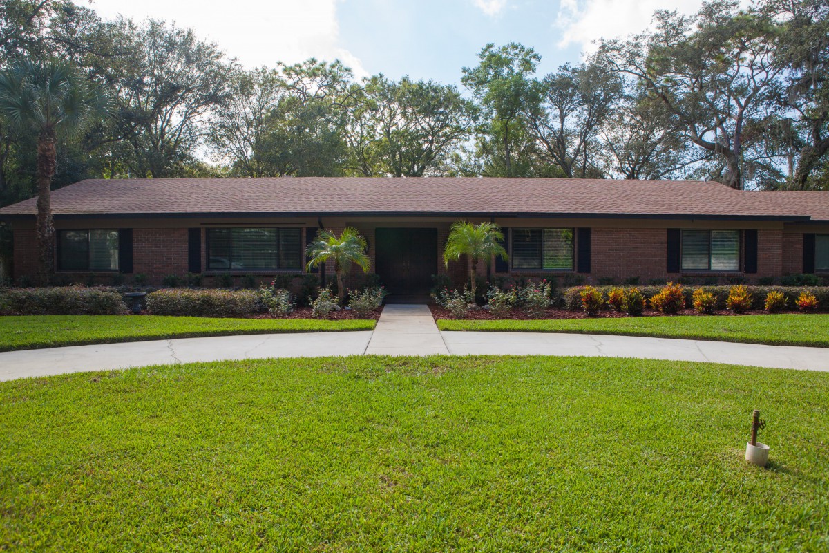 A single-story suburban house with a well-maintained front yard and surrounding trees.