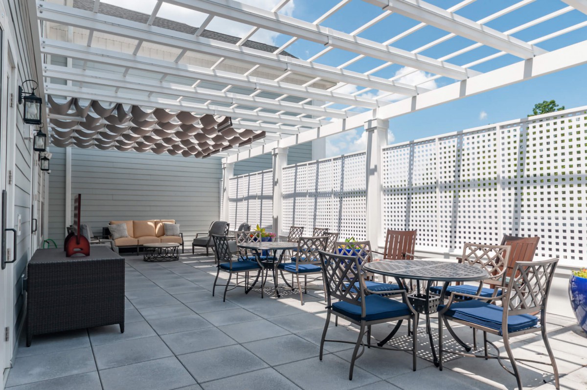 A modern rooftop patio with elegant furniture and a pergola providing shade.