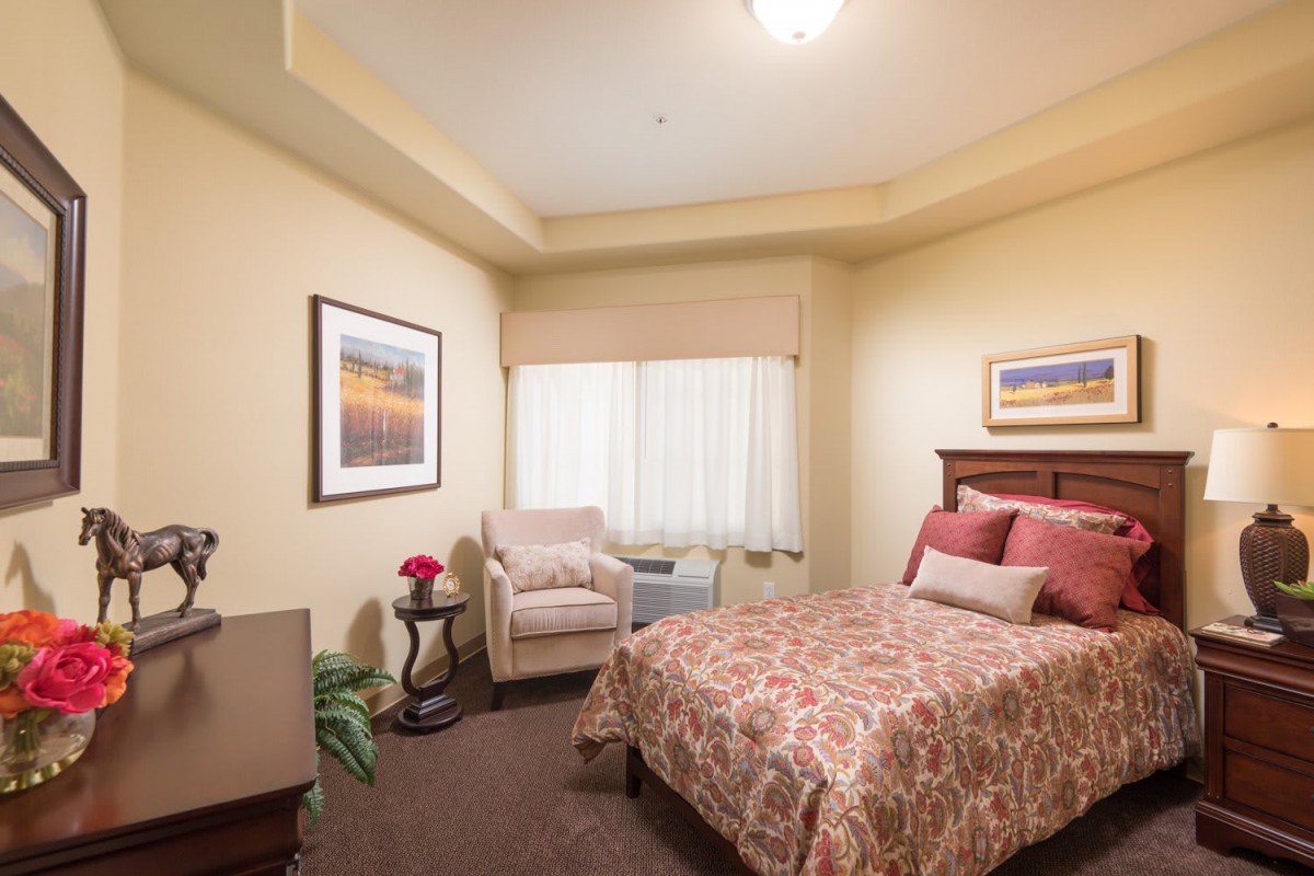 A cozy bedroom with a single bed, armchair, and artwork on the walls.
