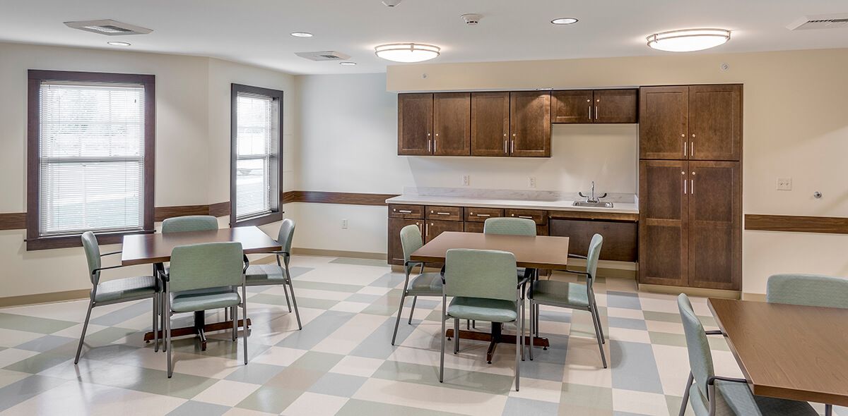 A modern kitchen and dining area with tables, chairs, and wooden cabinets.