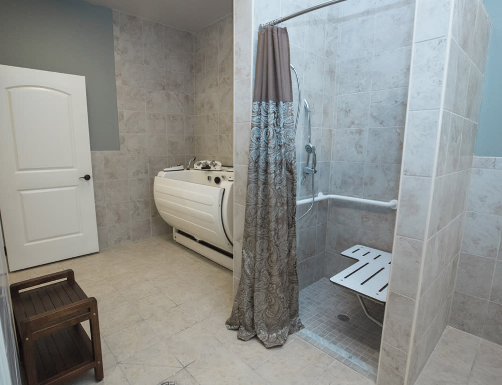 A modern bathroom featuring a bathtub and a walk-in shower with a curtain and built-in seat.