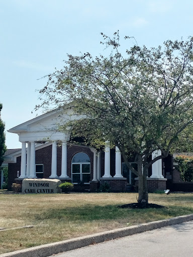 A stately building featuring classic architectural elements with columns, set against a backdrop of greenery.