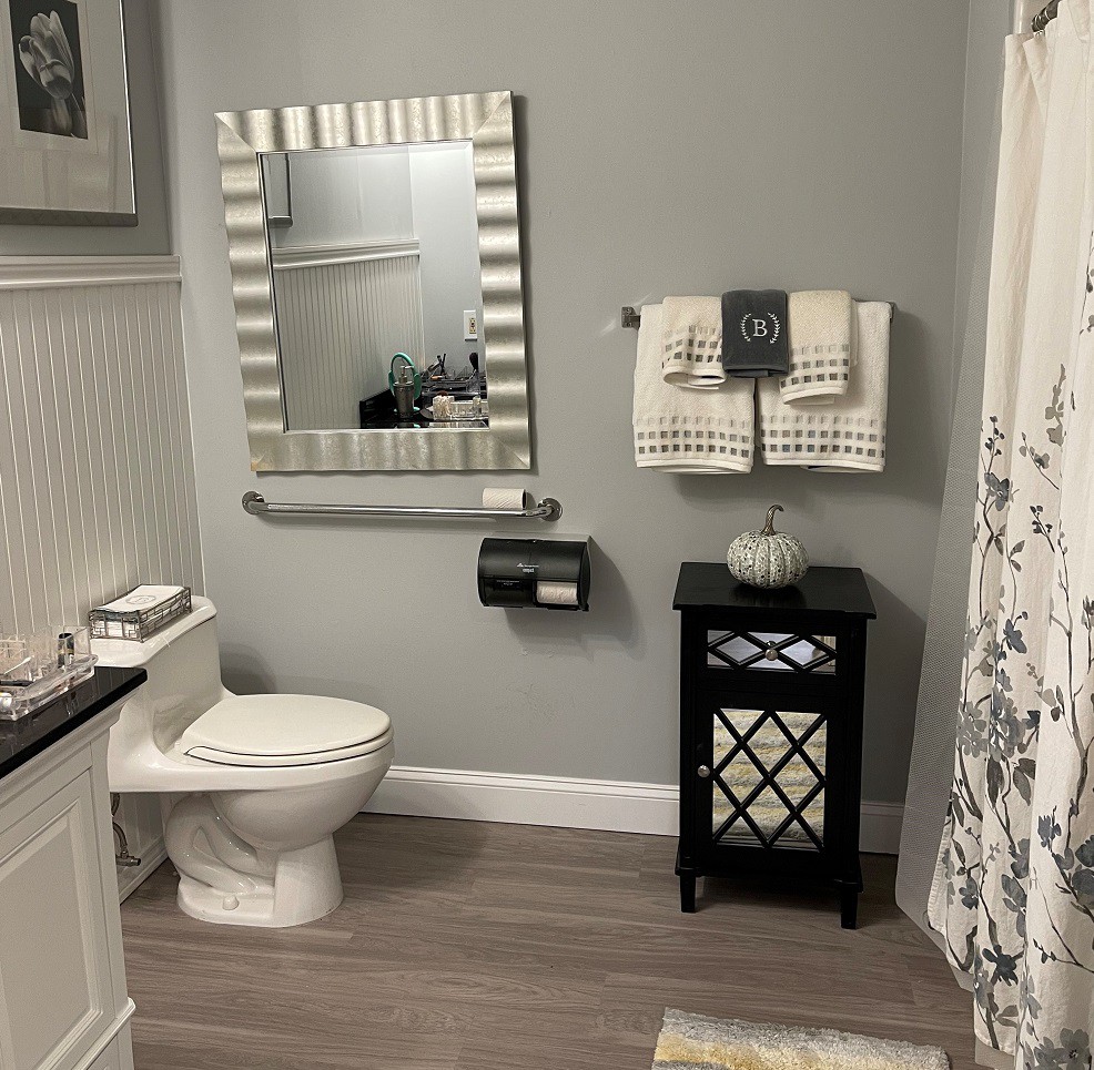 A modern bathroom with a decorative mirror, toilet, and storage cabinet.