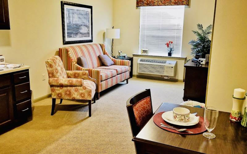 A cozy living room with a striped sofa, patterned armchair, and a small dining area.