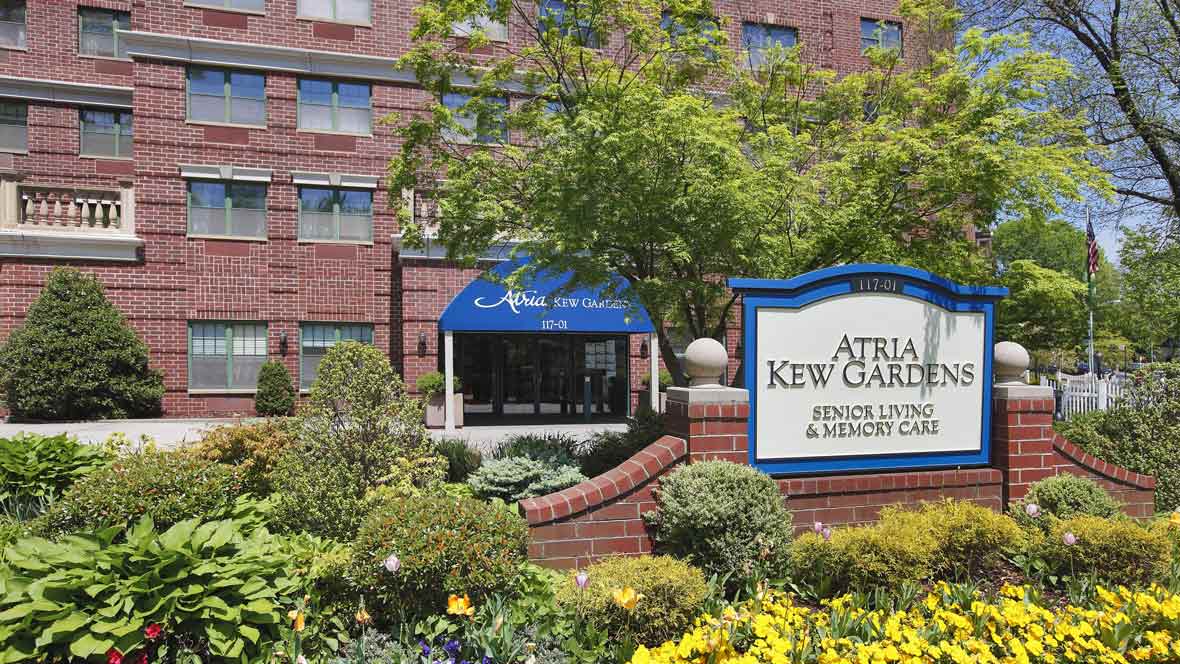 Entrance of Atria Kew Gardens, featuring well-maintained landscaping and signage.