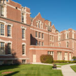 A historic brick building on a college campus under a clear blue sky.