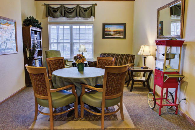 A cozy living and dining area with a round table, chairs, and a sofa near a window.
