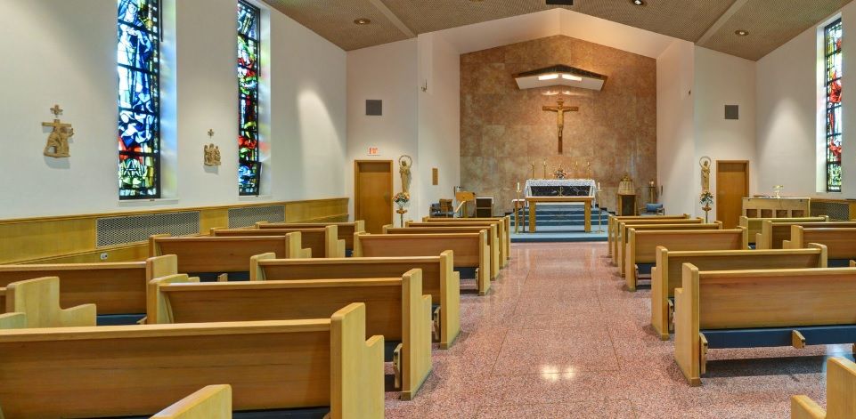Interior view of a church showing pews, altar, and stained glass.