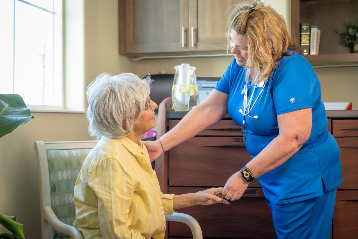 A nurse assisting an elderly woman in a healthcare setting.