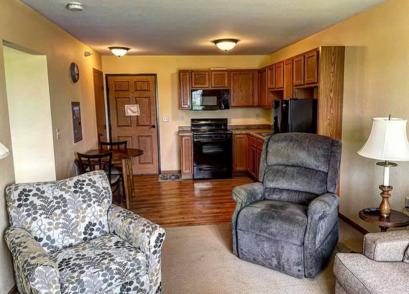 A cozy living area with a recliner and armchair adjacent to a kitchen space.