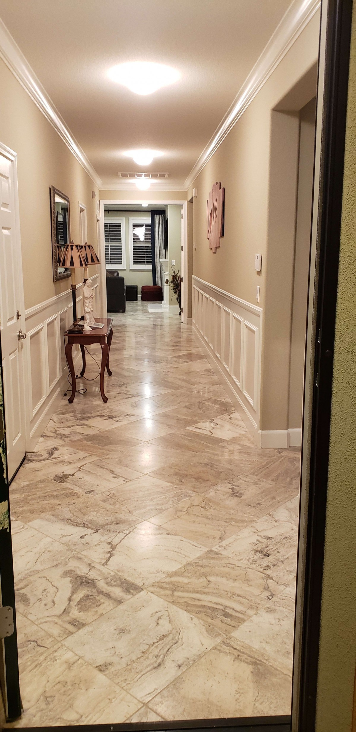 A well-lit hallway with marble flooring and classic decor.