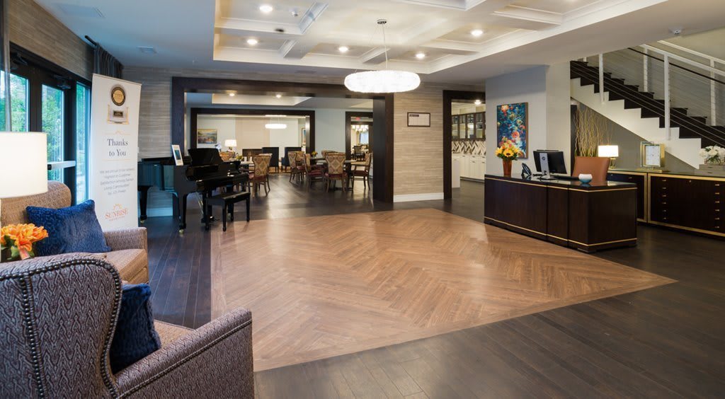 A modern hotel lobby with a reception desk, seating area, and piano.